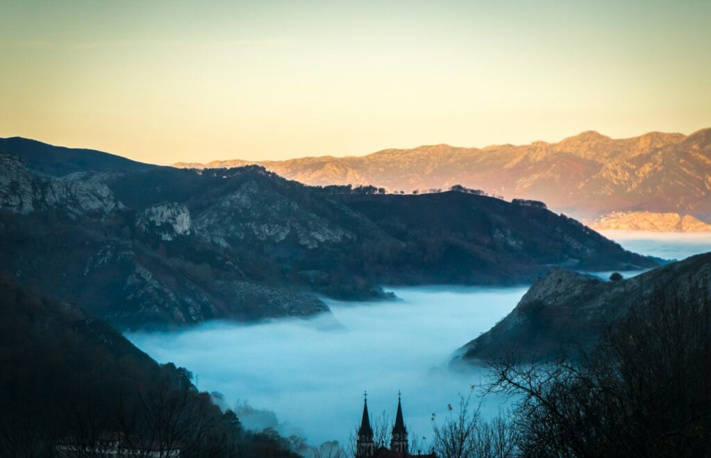 landscape photo of fogs between gray mountains at daytime