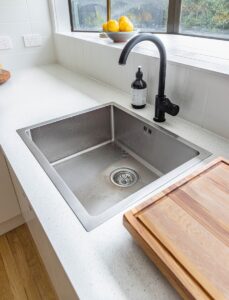 Woman using baking soda and brush to clean sink, closeup